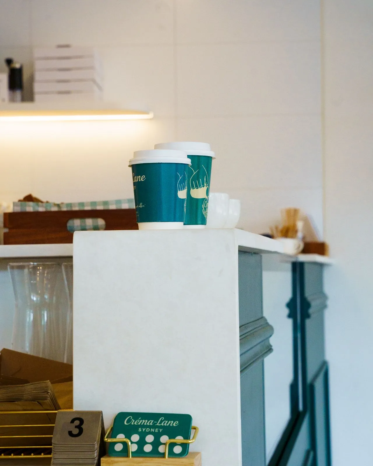 Takeaway cups on Créma-Lane's white stone counter