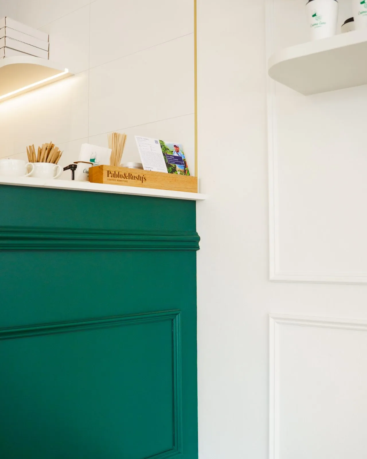 Créma-Lane counter detail: green panelled joinery, brass reveal and floating shelf